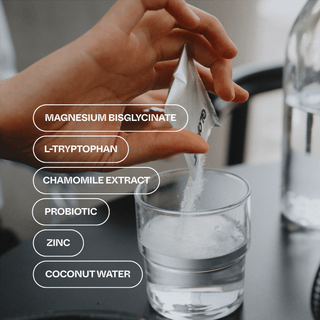 Hand pouring a supplement into a glass of water with listed ingredients.