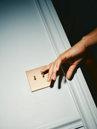 Hand reaching for a gold doorknob on a white door