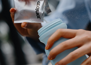Person holding a clear plastic bag with 'GloJuice' branding and a blue container.