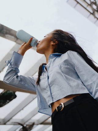 Women drinking wellness supplement in city setting