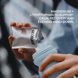 Person holding a GloJuice supplement packet with text about magnesium and L-tryptophan benefits.